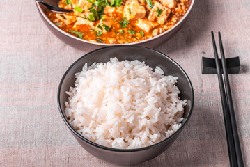 Traditional Chinese Sichuan cuisine - a bowl of rice and mapo tofu in a large plate on a rustic table