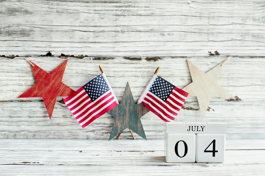 Fourth of July Background. Wood calendar blocks with the date July 4th to mark America's Independence Day. American flags with a star shaped banner hanging. 