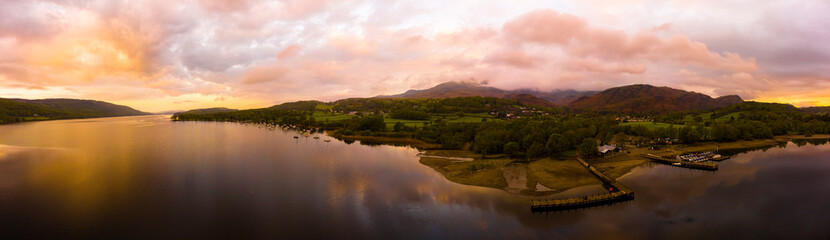 Aerial over the lake district Coniston lake during a dramatic sunrise surrounded by mountains, England panoramic
