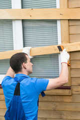 a man kicks nails into planks on a window, closes them from natural disasters