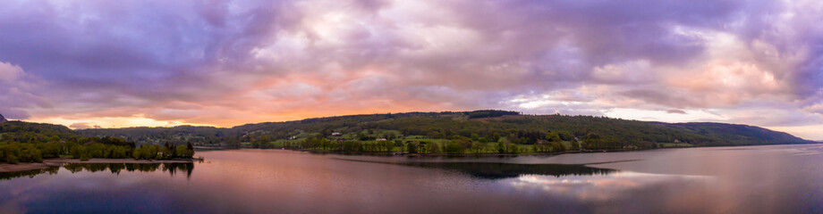 Aerial over the lake district Coniston lake during a dramatic sunrise surrounded by mountains, England panoramic