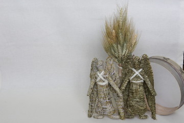 An amulet of dolls holding an angel from hay and a dry flower of handmade. Dry shoots, wheat, rye. The concept of goodness, wealth, crop.