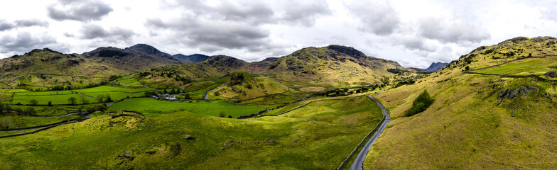 Fototapeta na wymiar Aerial over the lake district with mountains and hills and dramatic sky, England panoramic