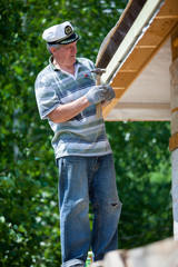 A man is repairing a roof standing on the stairs