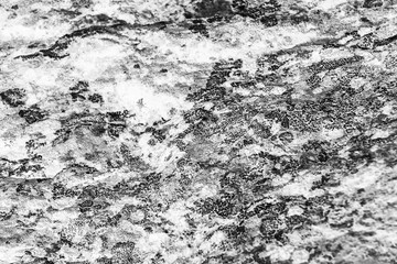 Vintage monochrome background. Rough painted wall of black and white color. Imperfect plane of grayscale. Uneven old decorative backdrop. Texture of black-white. Monochromatic ornamental stony surface