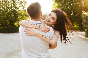 Portrait of a happy couple in love and embracing summer outdoors. Woman shows her hands with the...