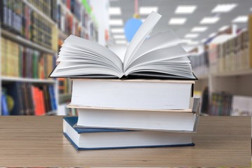 Open book, hardback books on wooden table.