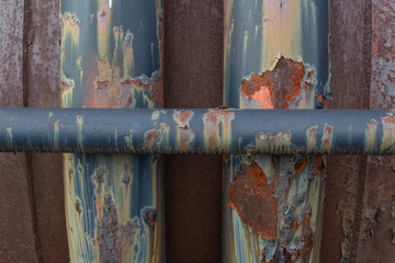 Background of painted and unpainted industrial metal pipes, peeling and rusted textures, horizontal aspect