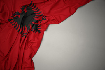 waving national flag of albania on a gray background. - obrazy, fototapety, plakaty