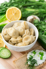 boiled meat dumplings in a plate, greens on a cutting Board, bread with yogurt and herbs