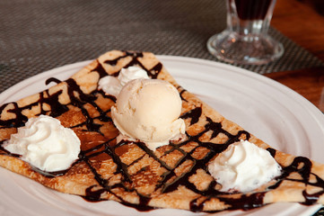 French pastry crepe with vanilla ice cream on white plate