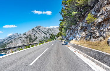 Naklejka premium Mountain highway with blue sky and rocky mountains on a background