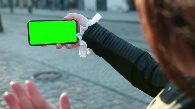 Girl speaks on a smartphone the greenscreen of the phone. Waves the hand to the people that they see on the screen. Having fun, technologies. Close up view, slow motion. Prores, 4k