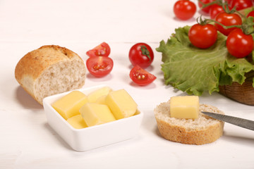 Ripe fresh Juicy organic brunch of cherry tomatoes on cutting board with Green Lettuce, bread, butter on a white table