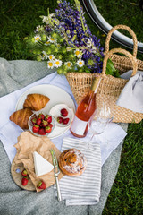 Obraz na płótnie Canvas Beautiful summer picnic with strawberries, cheese and rose wine on the lawn in the city park