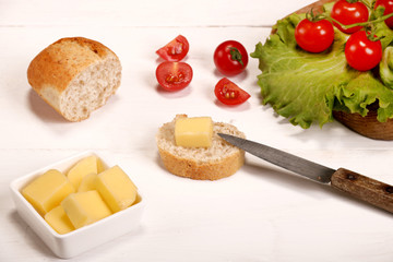 Ripe fresh Juicy organic brunch of cherry tomatoes on cutting board with Green Lettuce, bread, butter on a white table
