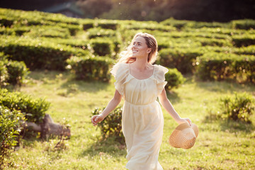 Inspired cheerful young woman millenial in light peasant dress runs across green grass through...