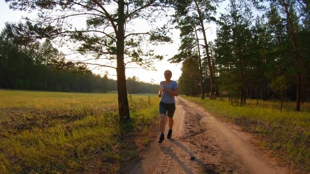 Girl in shorts and blue glasses running on a country road at sunset. Slow motion