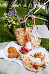 Beautiful summer picnic with strawberries, cheese and rose wine on the lawn in the city park