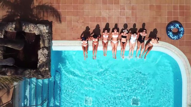People having fun in summer at the pool with trendy coloured inflatable mattress lilos - couple of beautiful girls lay down and enjoy the sunny day together - aerial view and hotel resort concept vaca