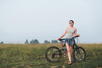 Fototapeta na wymiar white caucasian young woman in casual clothing standing with bicycle in field, full body size view, lifestyles stock photo image