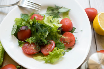Vegetable salad with fresh lettuce, tomatoes and cucumber in clay pot. Top view.