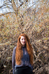 Portrait of young redhead woman in autumn park