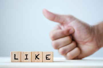 Like keyword on wooden cubic and fist showing thumb up gesture.-Image