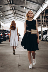 Stylish young girl dressed in a comfortable, daily black dress and white sneakers pose for a photo on an industrial background, urban clothing style. Street photography