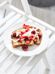 French toast with berries and mascarpone cheese on a light background.