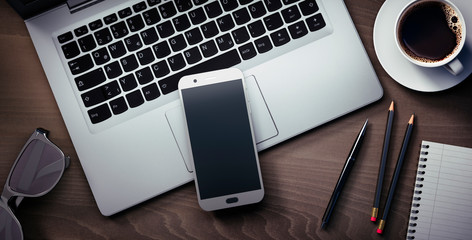 Smartphone und Laptop auf dunklem Holz
