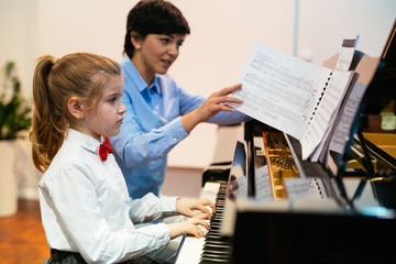little girl playing piano her professor assistance
