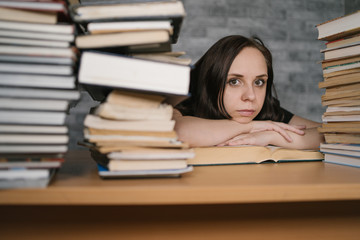 Beautiful woman student studying with a lot of paper books on the table