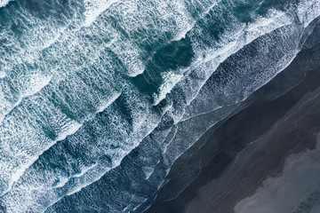 Aerial drone view of ocean waves spashing black sand beach, Iceland