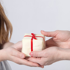 Female hands holding small gift with ribbon.