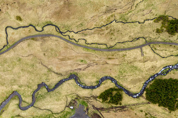 Aerial view of winding small river, stream in green field in Iceland