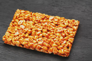 Golden boletus kozinaki from roasted peanut beans energy bars. Black textural background, top view