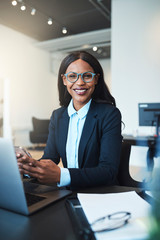 Smiling African American businesswoman sitting at work using a c