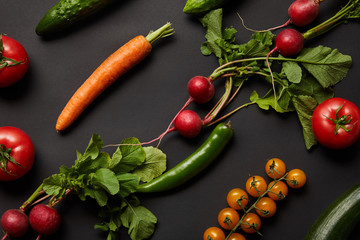 Fototapeta na wymiar raw nutritious tasty vegetables with green leaves on black background
