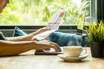 Businessman work on laptop checking invoice with coffee on wooden table.