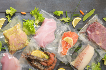 Sous Vide cooking concept. Vacuum packed ingredients arranged on wooden dyed background. Top View.
