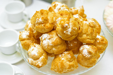 a lot of eclairs on the plate. delicious fresh donuts with powdered sugar.
