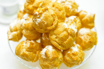 a lot of eclairs on the plate. delicious fresh donuts with powdered sugar.