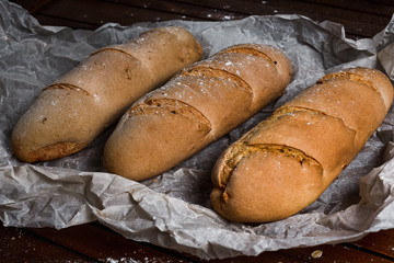 tasty bread on white paper on brown wooden board