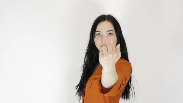 Young woman on a light background. She is showing an indecent gesture.