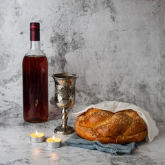 Shabbat Shalom - challah bread, shabbat wine and candles on grey background