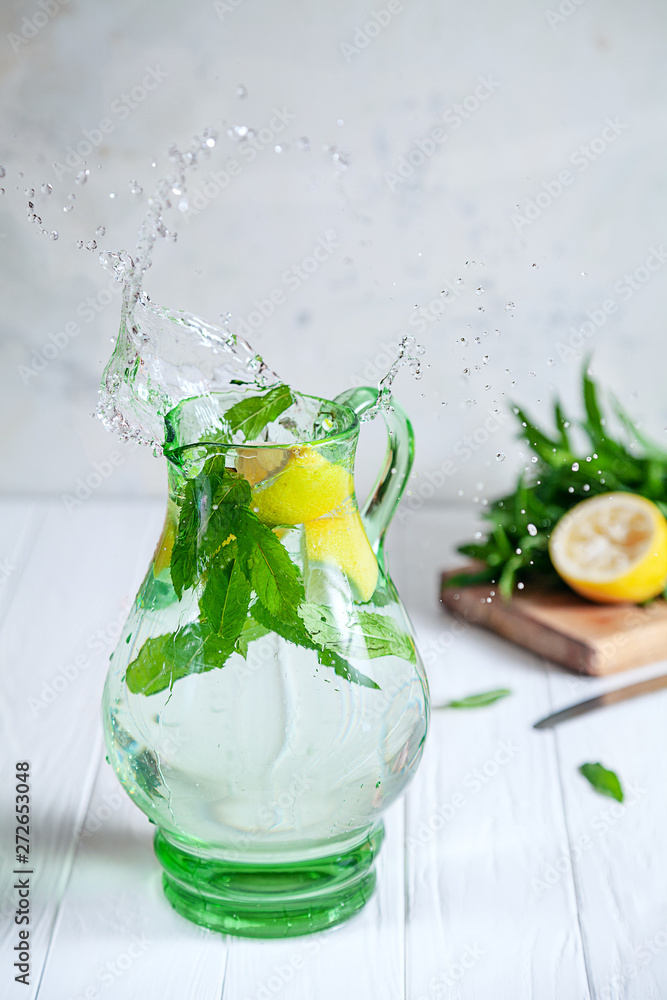 Wall mural Lemon make splash in pitcher or jar. Natural lemonade splash in jar with water, lemon and mint. Refreshing, cold drink. Concept of healthy, detox. glass jar with splashes. Food in motion concept