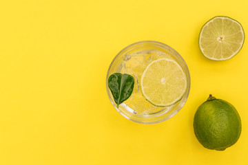 Gin tonic cocktail drink in glass on summer yellow background