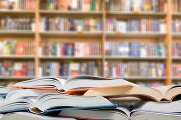 Stack of open school books on library background