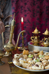 Oriental tea tray and cookies symbolising Moroccan hospitality, Islamic holidays food with decoration. Ramadan kareem. Eid mubarak. Oriental hospitality concept. Tea glasses and pot, traditional delig